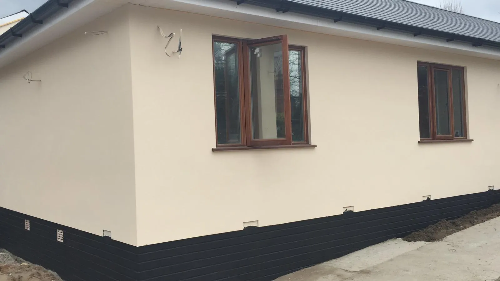 New bungalow with cream render and dark plinth